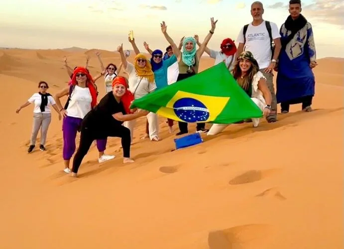 Best small group tours to Morocco – excited international group on Sahara sand dunes in Merzouga