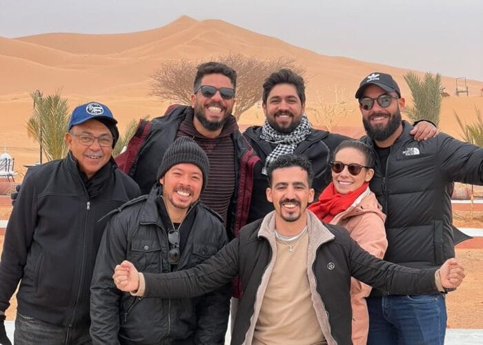 group of friends at Erg Chebbi dunes in Merzouga desert; Your Morocco small group tour includes time to explore and enjoy the legendary Erg Chebbi dunes in Merzouga.
